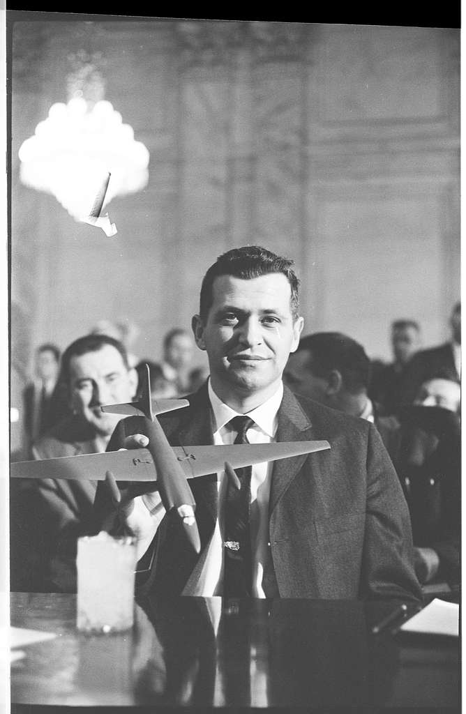 Francis 'Gary' Powers sat behind a desk holding up a model plane.